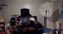a man wearing a top hat and glasses is sitting in front of a microphone in a room