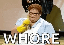 a woman wearing yellow rubber gloves is sitting on a table with the word whore written on the screen .