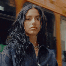 a woman with long dark hair wearing a denim jacket