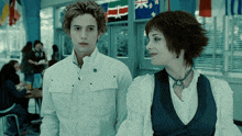 a man and a woman standing next to each other in a hallway with flags in the background