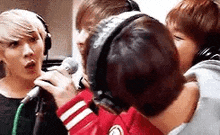 a group of young men are singing into microphones in a studio .