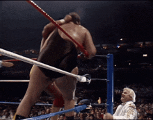 a man in a white suit stands in a boxing ring