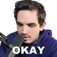 a man in a blue hoodie is sitting in front of a microphone and the word okay is on the bottom of his face