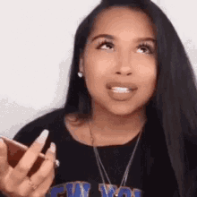 a woman is holding a cell phone in her hand and talking on it .