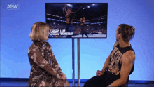 a man and a woman are sitting in front of a television screen that says aew last wednesday