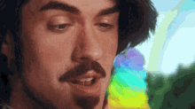 a close up of a man 's face with a rainbow background