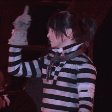 a woman in a black and white striped shirt holds up her hand