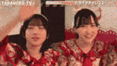two girls are standing next to each other in front of a sign that says takanekotv