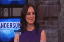 a woman in a purple dress stands in front of a screen that says anderson