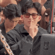 a man wearing sunglasses is covering his mouth with his hand