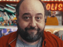 a man with a beard and headphones is smiling in front of a sign that says " olio "