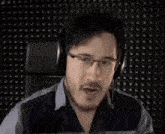 a man wearing headphones is making a funny face while standing in front of a black wall .