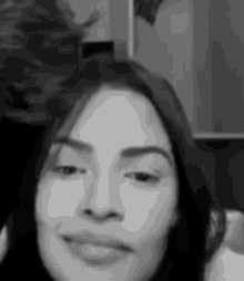 a black and white photo of a woman 's face with a man in the background .