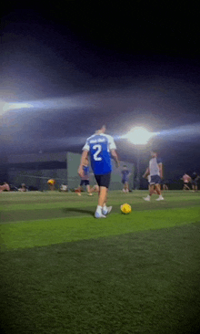 a man wearing a blue jersey with the number 2 on it kicks a soccer ball
