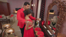 a man in a red suit adjusts a woman 's necklace