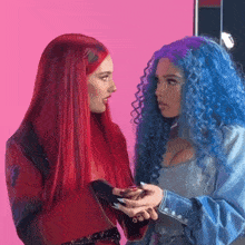 a woman with red hair and a woman with blue hair are looking at each other