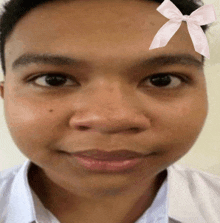 a close up of a man 's face with a pink bow on his forehead .