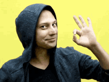 a man wearing a hooded jacket is giving an ok sign