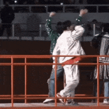 a group of people are dancing in front of a red fence
