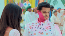 a man with holi paint on his face is standing next to a woman in a white dress