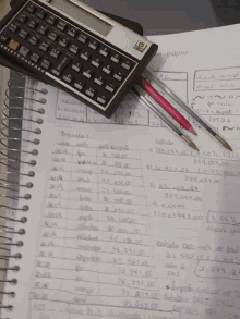 a hp calculator is on top of a notebook