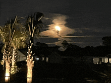 a full moon is shining through the clouds over a residential area
