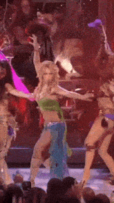 a woman in a green top and blue skirt is dancing on stage