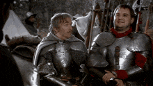 two men in armor are sitting next to each other and talking to each other .