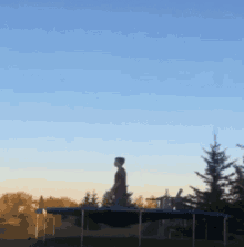 a person is jumping on a blue trampoline with a blue sky in the background