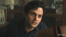 a man in a blue shirt is sitting in front of a sign that says old fashioned netflix