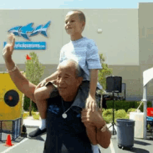 a man is carrying a young boy on his shoulders in front of a building that says aquariums