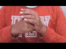 a person wearing a red sweater with the letters tsv on it