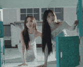 two women with long hair are standing next to each other in front of a blue door