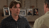 a man in a plaid shirt talks to a woman and another man