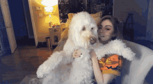 a woman sitting on a couch holding a white dog