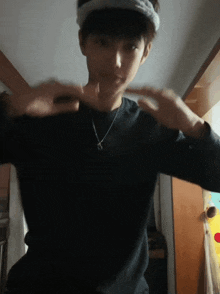a young boy wearing a black shirt and a white headband is making a heart shape with his hands