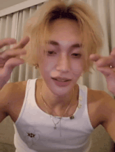 a young man wearing a white tank top and a necklace