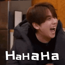 a young man is laughing with his mouth open and the words `` hahaha '' written on the bottom .