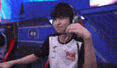 a man wearing headphones and a shirt that says rox esports on it