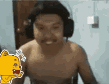a man without a shirt is wearing headphones and a cartoon cat is behind him