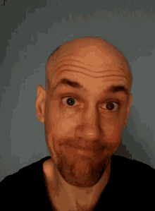 a bald man with a beard makes a face