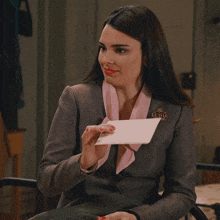 a woman wearing a grey jacket with a pink collar and a pin that says reina