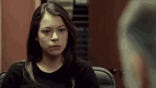a woman in a black sweater sits in a chair