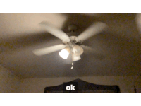 a ceiling fan is turned on in a dark room with an ok sign in the corner