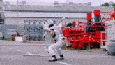 a mascot is standing in a parking lot in front of a large red machine