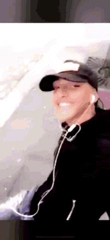 a man wearing a hat and headphones is smiling and taking a selfie .