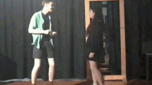 a man in a green shirt is standing next to a woman in a black dress