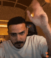 a man with a beard is wearing a white t-shirt with the letter u on the front