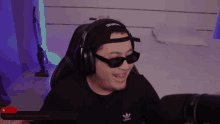 a man wearing headphones and sunglasses is sitting in front of a microphone with a purple background
