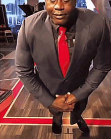 a man in a suit with a red tie is kneeling down